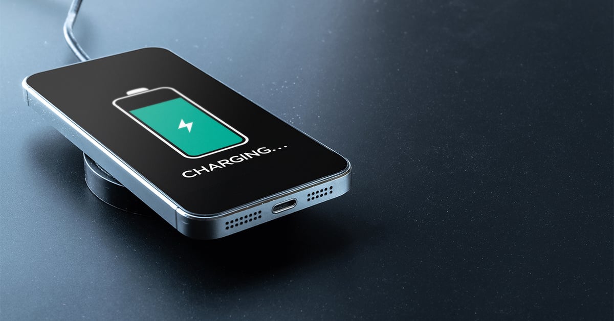 Smartphone wirelessly charging on a sleek black surface, displaying a green battery icon with a lightning bolt symbol.