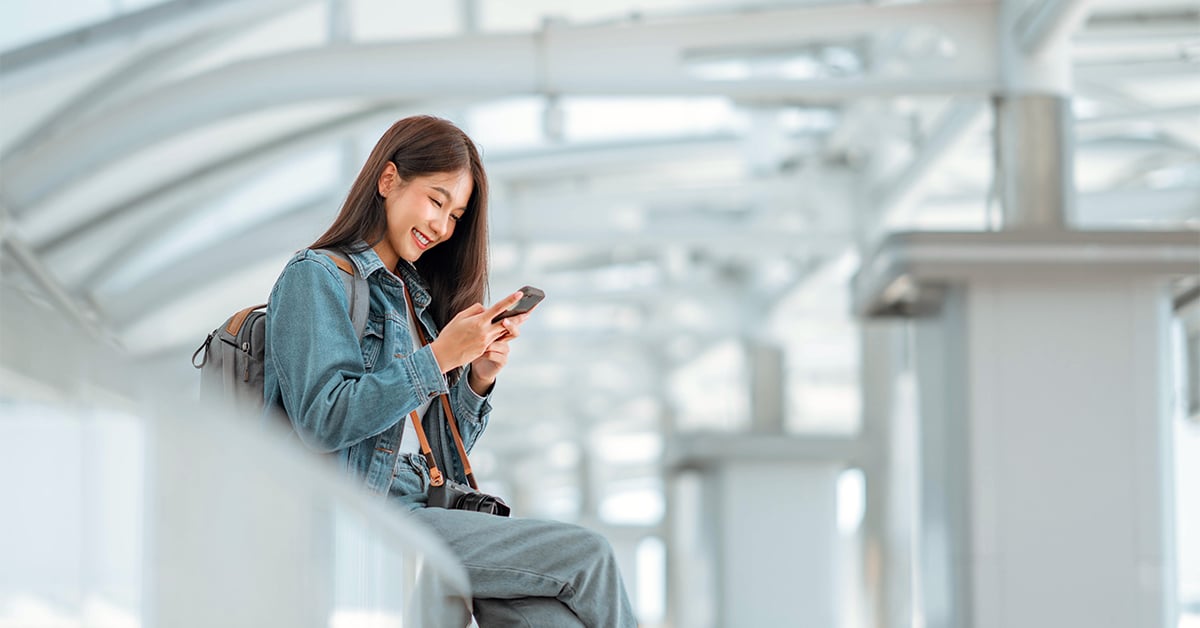 woman looking at phone while traveling airport train station